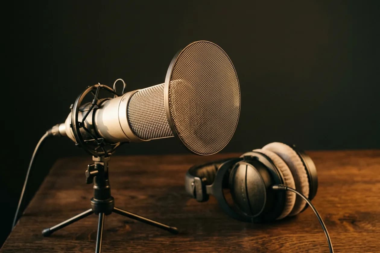 Mikrofon studyjny z pop filtrem i słuchawki na drewnianym biurku